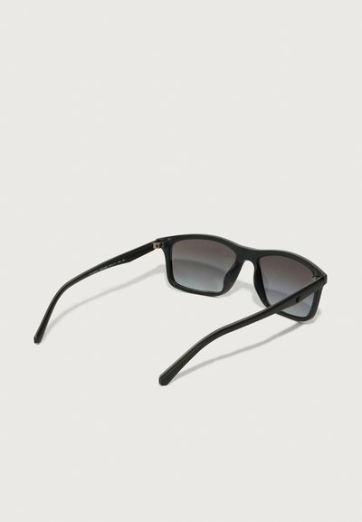 Occhiali da sole neri con montatura quadrata, lenti sfumate e aste sottili. Presentano una finitura opaca e un design minimalista.