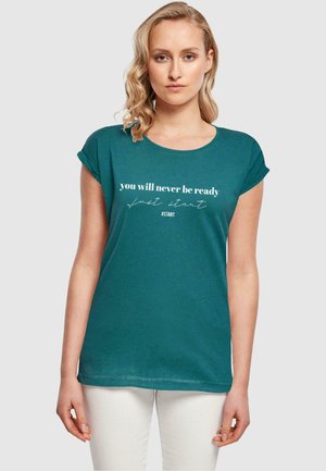 T-shirt teal à manches courtes avec un col rond. Le devant présente un texte blanc : "tu ne seras jamais prêt, commence juste #START." Design simple.