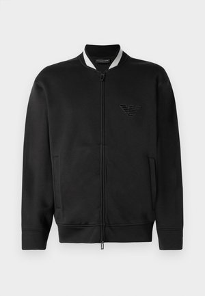 Black bomber jacket with a zip front, ribbed collar, and embroidered logo. Features two side pockets and a smooth fabric texture.