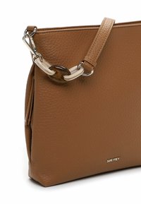 Borsa a tracolla in pelle marrone con una superficie testurizzata, dotata di una tracolla staccabile con anelli trasparenti e marroni. Tasca con cerniera sul lato.