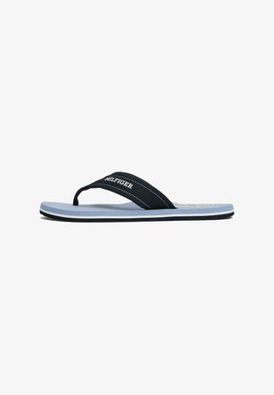 Schwarze Flip-Flop-Sandale mit einem weichen, breiten Riemen, der mit weißem Logo-Text versehen ist, einem hellblauen Fußbett und einer dunklen Gummi-Sohle.