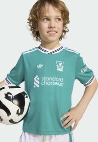 Turkizna nogometna majica Liverpool FC z ovratnikom in poudarki na rokavih v črno-belih črtah, z logotipom "Standard Chartered" in emblemom Adidas.