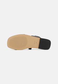 Semelle de chaussure noire avec une surface beige lisse et des rainures pour l'adhérence. Présente un talon rond, et la taille marquée 7,5M est imprimée.