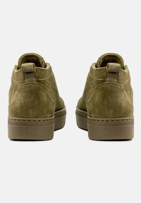 Gröna mocka ankboots med en texturerad yta, rund tå och förstärkt bakflik. Har en beige gummisula och sömnadsdetaljer.