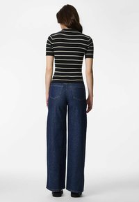 Crna i kremasta prugasta kratka majica s rebrastim uzorkom uparena s visokim širokim tamnoplavim trapericama, s prikazom stražnjih džepova i širokim krojem.