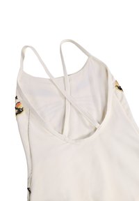 Λευκό τοπ με λεπτές τιράντες και σταυρωτές τιράντες στην πλάτη, με μικρές πολύχρωμες κεντητές πεταλούδες κοντά στις πλευρές.