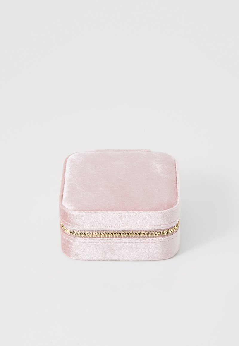Square jewelry box in soft pink velvet with a gold zipper. Smooth texture, minimalistic design, and padded top for protection.