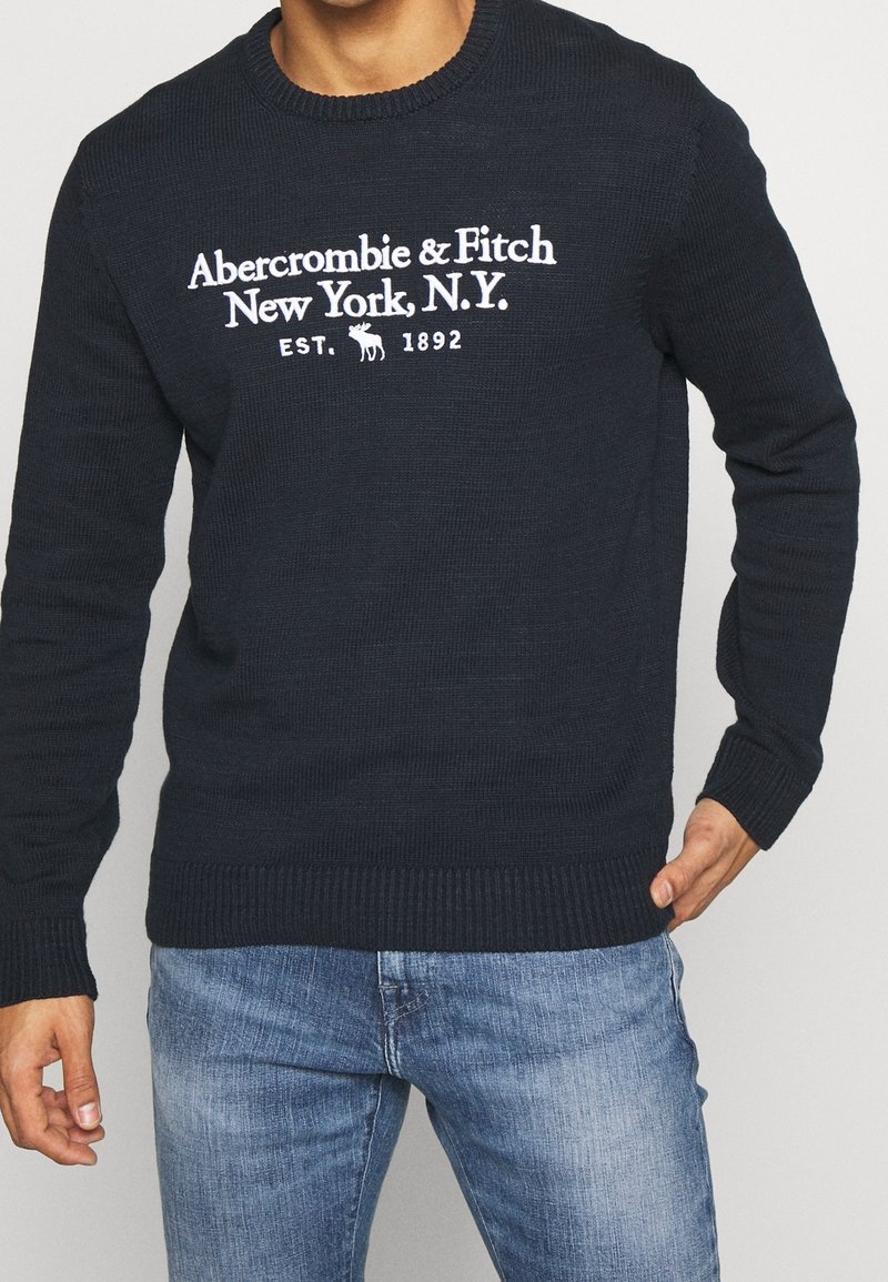 Maglione lavorato a maglia di un blu scuro, con collo a giro e testo bianco "Abercrombie & Fitch New York, N.Y." e polsini e orlo a coste.