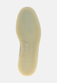 Suela de zapato de goma en beige claro con un patrón de espiga y un acento de marca. Acabado suave con una ligera curva a lo largo del borde.