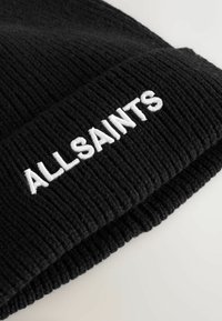Černá žebrovaná pletená čepice s ohrnutím, na přední straně zdobena bílým vyšitým textem "ALLSAINTS". Měkká textura, neformální design.