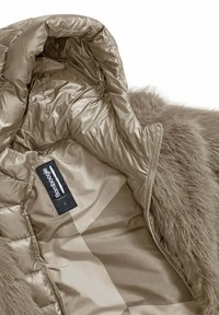 Pufferjack met een satijnen buitenlaag in taupe, voorzien van een zachte nepbont kraag en een gladde binnenvoering. Merkenlabel zichtbaar.