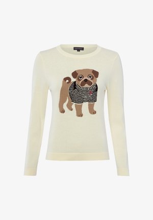 Pull à manches longues couleur crème avec un motif tricoté représentant un chien brun portant un pull rayé noir et blanc à l'avant.