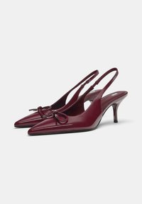 Bordo lakirani sandali s potpeticom i oštrim vrhovima, s ukrasnom mašnom i tankom, prozirnom potpeticom.