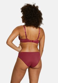 Conjunto de ropa interior burdeos con una tela suave, tirantes ajustables y un corte clásico de bikini. Costuras mínimas y sin piezas de hardware visibles.