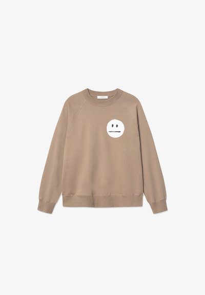 Sweatshirt marron avec des poignets et un ourlet côtelés, arborant un grand graphique de visage souriant blanc sur la poitrine gauche. Fabriqué en mélange de coton doux.