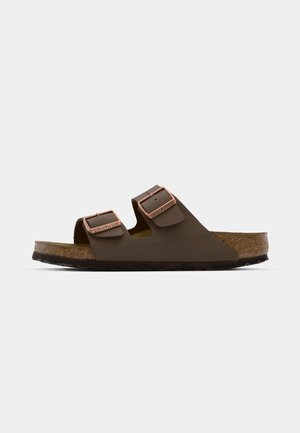 Brown two-strap sandal with copper-tone buckles, cork footbed, and rubber outsole. Sleek design with adjustable straps for fit.