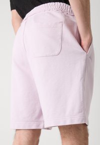 Lyserøde bomuldsshorts med elastisk talje. Har en enkelt baglomme og sidelommer. Glat tekstur med en afslappet pasform.