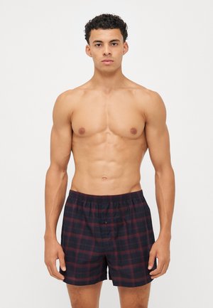 Men's plaid boxers in navy and burgundy, featuring an elastic waistband and a single button closure, made from a lightweight cotton blend.