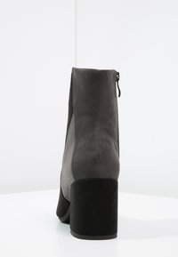 Stiefelette aus grauem Wildleder mit glatter Oberfläche und klobigem schwarzen Absatz. Verfügt über einen seitlichen Reißverschluss für einfaches An- und Ausziehen. Schlichtes, elegantes Design.