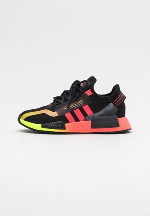 Baskets Adidas noires avec des accents jaune néon et orange, des rayures rouges et un texte rouge sur la languette du talon, vues de côté extérieur sur fond blanc.