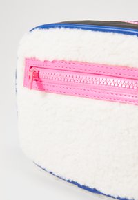 Borsa in pelliccia sintetica bianca con fondo blu, caratterizzata da una zip rosa brillante sulla parte anteriore e dettagli in superficie testurizzati.