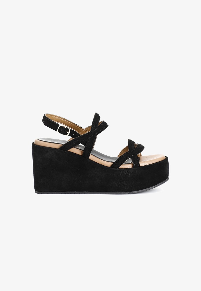 Černé semišové sandály na klínku mají křížové řemínky, nastavitelné zapínání kolem kotníku a nahou stélku. Texturovaná platforma pro větší výšku.