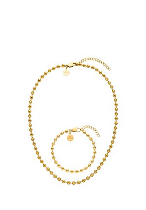 Goldfarbene Perlenkette und passendes Armband mit runden Verschlüssen und kleinen runden Markenzeichen auf weißem Hintergrund.