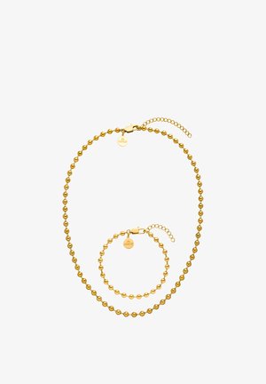 Goldfarbene Perlenkette und passendes Armband mit runden Verschlüssen und kleinen runden Markenzeichen auf weißem Hintergrund.