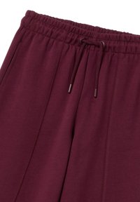 Burgunderfarbene Sweatpants mit elastischem Bund und Kordelzug. Mit Seitennähten und einem weichen, strukturierten Stoff.