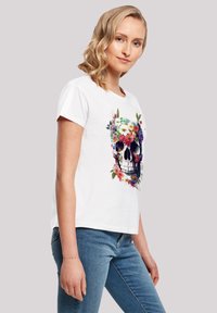 White cotton t-shirt featuring a colorful floral skull design, short sleeves, crew neck, and a relaxed fit.