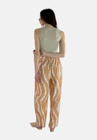 Lichtbeige, aansluitend tanktop gecombineerd met losse, gemusterde broek in perzik- en crèmekleuren met een golfpatroon en een elastische tailleband.