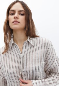 Camicia leggera a strisce in crema e marrone, maniche lunghe, colletto, taschino frontale, tessuto testurizzato con righe verticali.