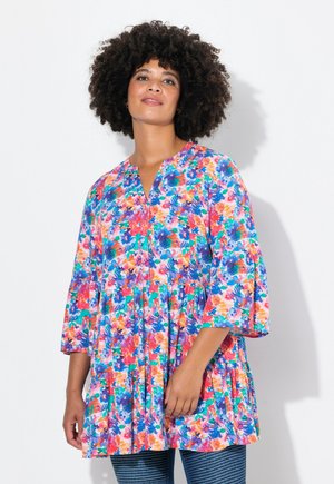 Tunique florale colorée avec un décolleté en V, des manches cloche trois-quarts et un ourlet froncé. Le matériau présente un motif vivant et texturé.