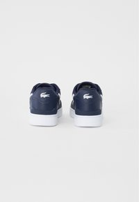 Marineblaue Sneakers mit glattem Lederfinish, weißer Sohle und kleinem weißen Logo an der Ferse, im klassischen Low-Top-Design.