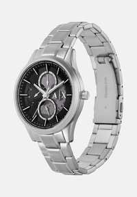 Roostevabast terasest kell, millel on must kellanägu, kolm alamkella, hõbedased kellanäpid ja metallist link-ranneke. Näo peal on kujutatud märk "A/X".