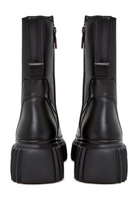 Botas de tobillo negras con un exterior de cuero suave, costuras reforzadas, suelas de goma texturizadas y cremalleras laterales para facilitar el uso.
