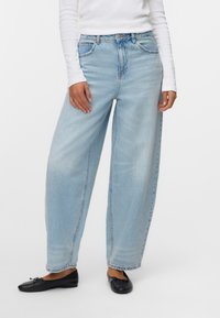 Svetle modré kalhoty s volným střihem vyrobené z denimu. Mají vysoký pas, přední kapsy a jemné vyblednutí. Vypadají dobře kombinované s černými plochými botami.