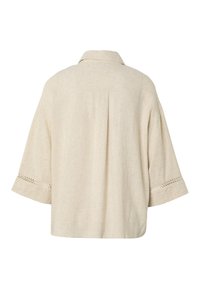 Chaqueta beige de corte holgado con mangas tres cuartos, ribete calado cerca de los puños, pliegue trasero y cuello clásico.