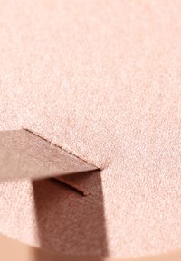 Superficie testurizzata color oro rosa con una lucentezza metallica e una sezione intagliata che rivela un bordo liscio. Presenta scintillii riflettenti e linee morbide.