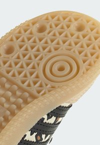 La suela exterior del zapato de goma presenta un patrón texturizado de panal en beige, con formas circulares y triangulares, que contrastan con la parte superior textil colorida.