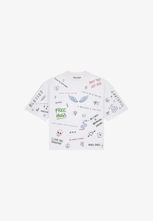 T-shirt bianca a maniche corte con frasi scritte a mano multicolore e scarabocchi che includono ali, serpente, teschio, cuori e simboli di pace.