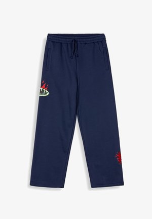 Marineblaue Jogginghose mit einem elastischen Bund, seitlichen Taschen und bunten Flammen- sowie Grafikakzenten am linken Oberschenkel. Weiche, glatte Textur.