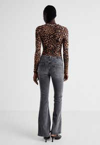 Langarm leopardprint top gecombineerd met grijze flared jeans. Gladde textuur, aansluitende silhouet en details van achterzakken.
