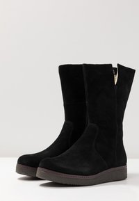 Black suede ankle boots with a rounded toe, elevated platform sole, and a mid-calf height. Features a side split and stitched accents.