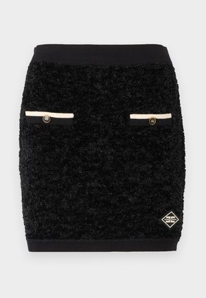 Čierna textúrovaná mini sukňa s dvoma prednými falošnými vreckami, ktoré sú lemované čierno-bielym pásikom a zdobené zlatými gombíkmi, a malou logo nášivkou v tvare diamantu.