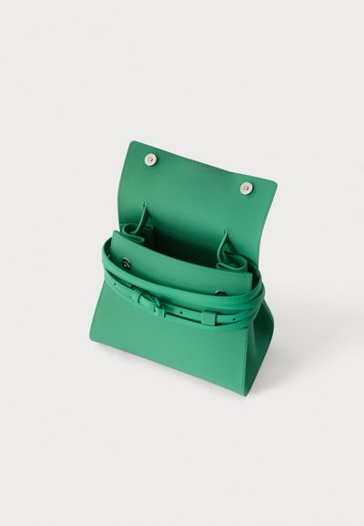 Πράσινη δερμάτινη τσάντα χειρός με ανοιχτό πάνω καπάκι, ασημένια κουμπώματα τύπου κλικ και ρυθμιζόμενο λουράκι στυλ ζώνης γύρω από το σώμα σε λευκό φόντο.