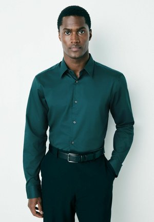 Dark teal long-sleeve button-up shirt with a structured collar, subtle texture, and matched with a black belt, worn with dark pants.