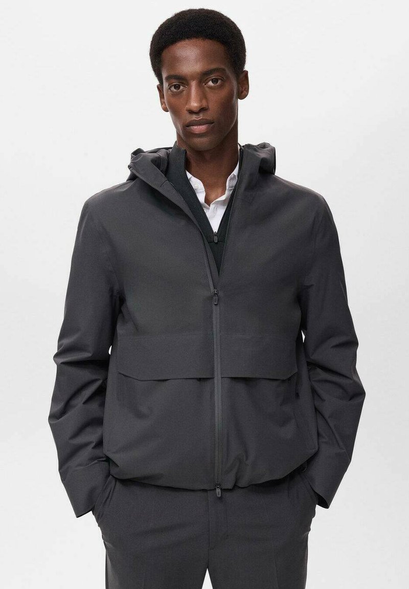 Grå zip-up jacka med huva, som har en framficka och en slät yta. Minimalistisk design utan synliga mönster eller detaljer.