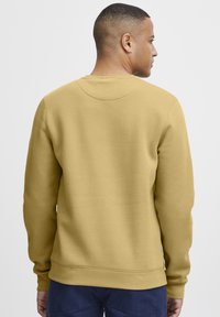 Yellow cotton sweatshirt with a crew neckline, ribbed cuffs, and hem. Smooth texture with no visible patterns or embellishments.