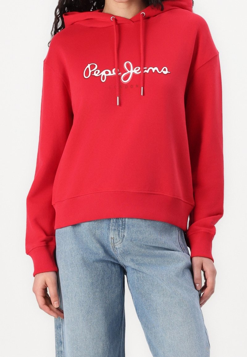 Rode hoodie met witte logo-tekst "Pepe Jeans London," met een losse pasvorm en geribbelde manchetten en zoom. Gecombineerd met een blauwe jeans.